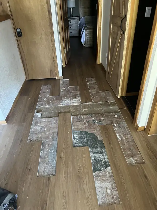 Vinyl plank floor repair in progress, with the cracked planks removed and the subfloor patched